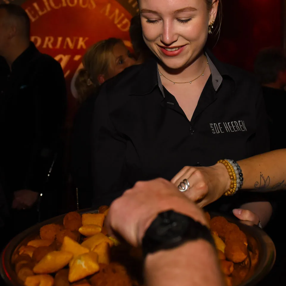 Medewerker van Café de Heeren brengt warme hapjes rond tijdens een besloten feestje in Purmerend