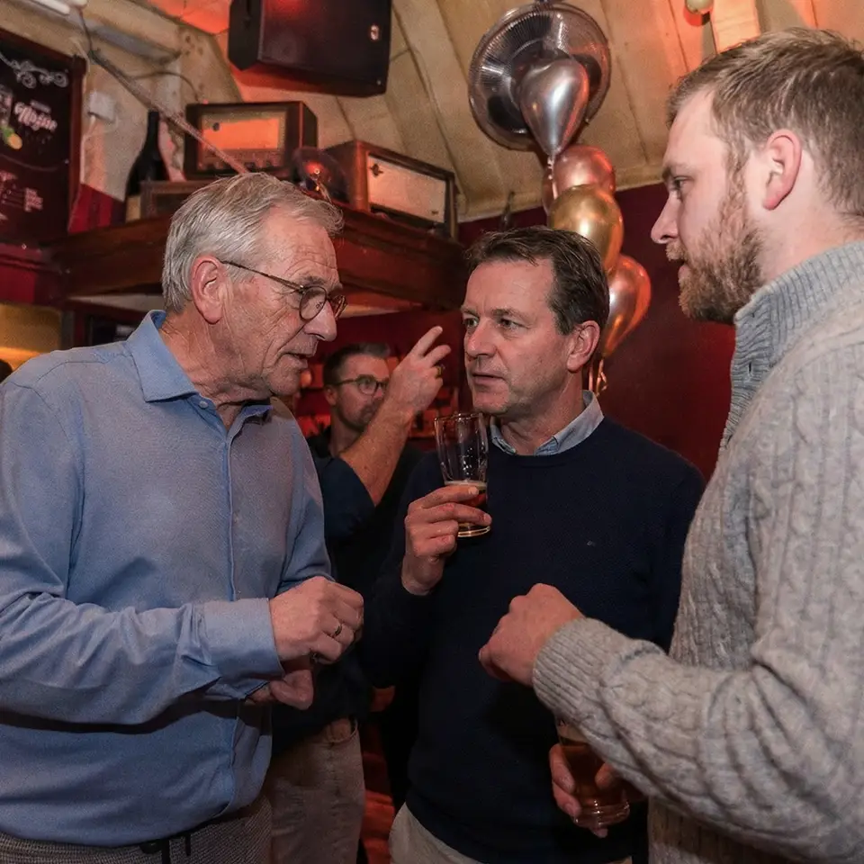 Gasten in gesprek met een biertje tijdens een borrel bij Café de Heeren in Purmerend