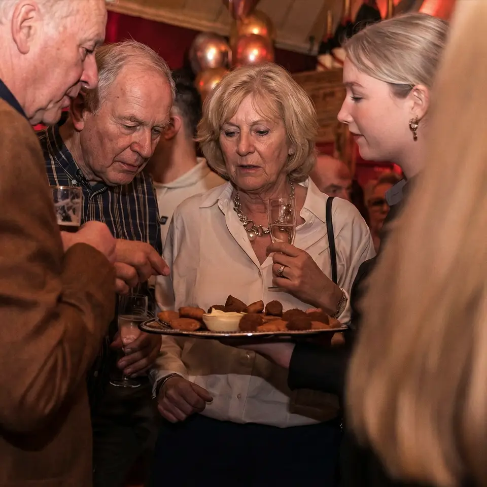 Gasten krijgen borrelhapjes geserveerd tijdens een pensioenborrel bij Café de Heeren in Purmerend